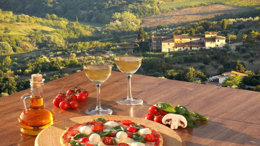italian-pizza-with-glasses-of-white-wine-against-tuscan-vine_shutterstock_1825209443.jpg